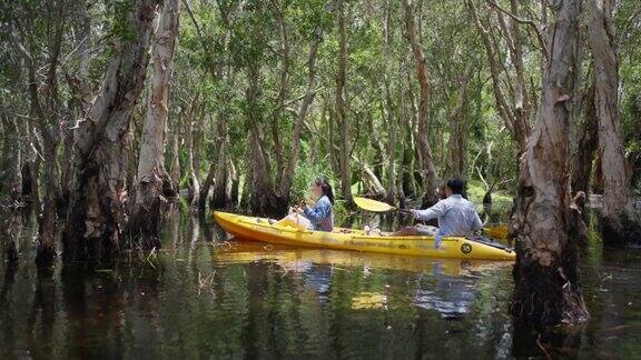 年轻的亚洲夫妇在夏季旅游假期的红树林划皮艇