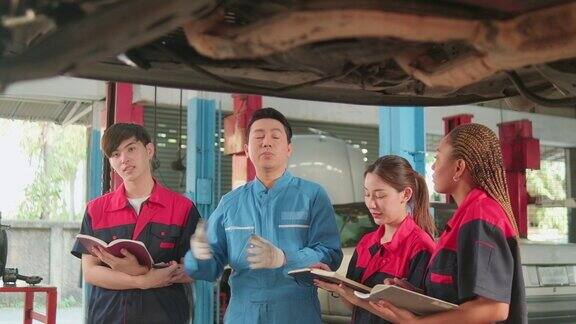 监工正在一家汽车修理厂教机械工人修理汽车