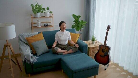 亚洲女性平静下来在家里用手做瑜伽的姿势深呼吸