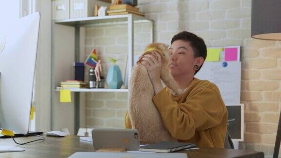 年轻的亚洲假小子女人穿着休闲装在家里的办公室里抱着她的猫