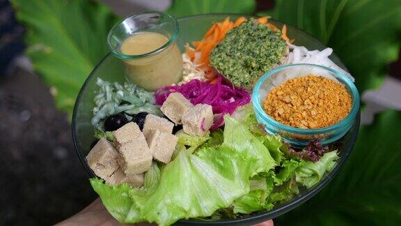 特写的一个大沙拉碗的素食蔬菜沙拉包括芝麻菜萝卜橄榄块豆腐奶酪胡萝卜西兰花甜菜在绿叶的背景