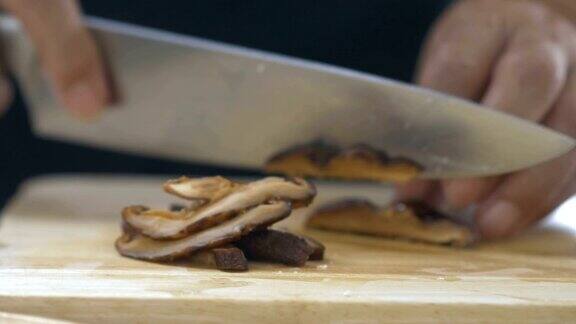 亚洲食物:女孩的手在木板上切蘑菇的特写