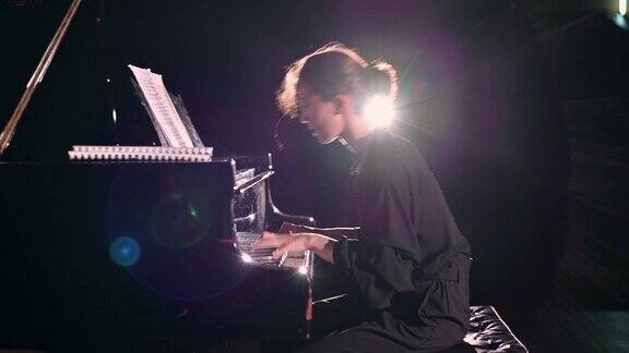 一位年轻女子在舞台的聚光灯下精力充沛地弹钢琴