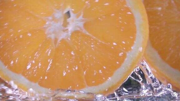 滚动的橙色水果片在黑色的背景慢动作镜头