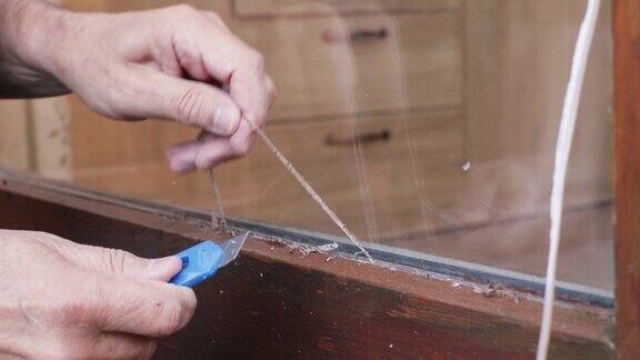 一个男人用刀清理旧硅胶绝缘层上的玻璃的特写