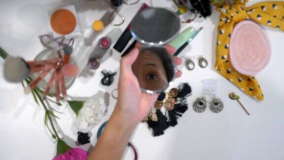 女人在化妆台用镜子用刷子擦粉底