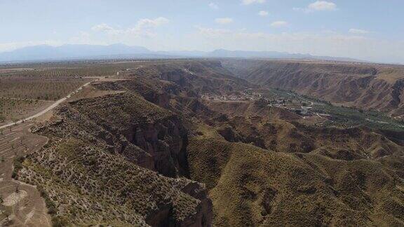 无人机在西班牙格拉纳达内华达山脉的蓝天中拍摄的GorafeDesiertodeloscolorado的干燥山谷和山脉在安达卢西亚有植被的西班牙沙漠峡谷跟踪4k