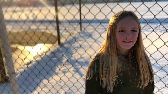 一个年轻美丽的女孩的肖像在一个小学附近的铁链围栏
