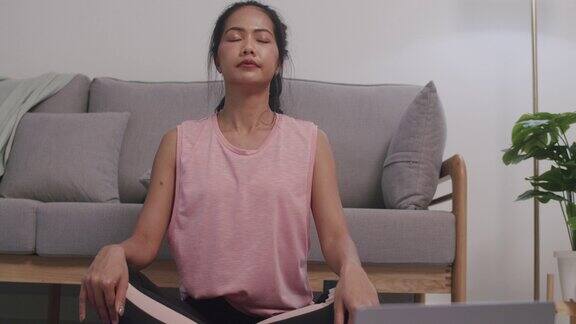 亚洲女性在家里的客厅里做运动训练和冥想