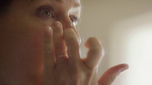 一位三十多岁的白人妇女用手指在眼睛下面化妆