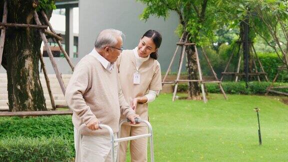 年轻的亚洲女性护理人员教老男性步行使用助行器在公园户外照顾牵手老人
