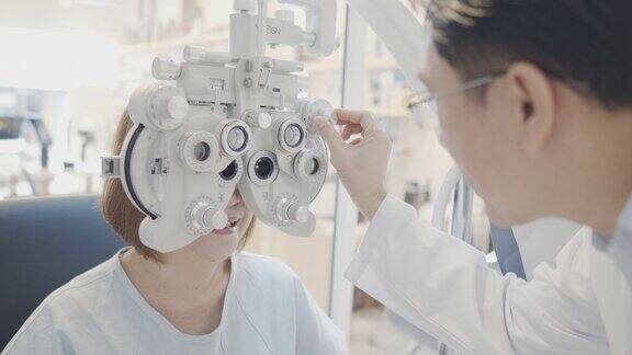 亚洲资深女性病人在验光店由医生检查眼睛使用自动折射仪、摄影仪、试验架、断线、视力表、监测图和眼检炬一位老年男性的眼部症状医学教育、医疗保健