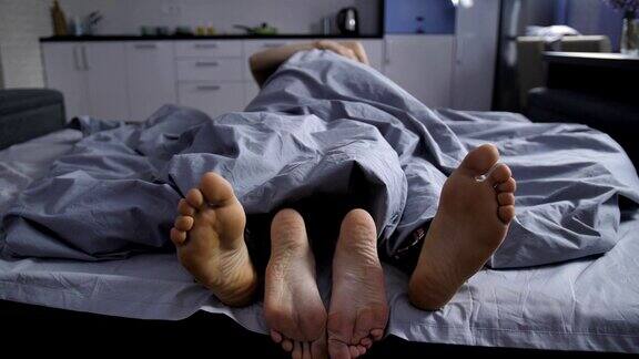 一对深情的夫妇在床上拥抱的脚
