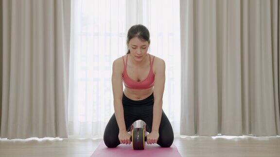 亚洲运动女是用滚轮腹肌轮运动机锻炼腹部和背部肌肉健身理念和健康
