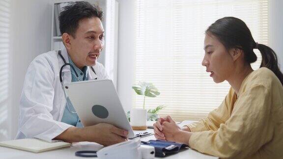 成熟的亚洲男性医生在健康门诊用平板电脑与女性患者会诊时的医疗结果