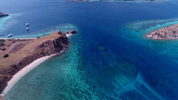 航拍干燥的岩石岛碧蓝的海水海湾里的潜水船