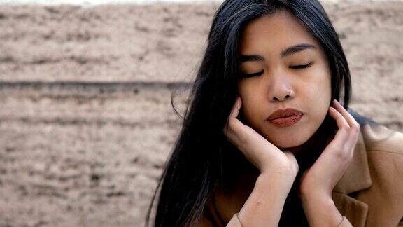 深思的沮丧的亚洲年轻女子独自在街上思考