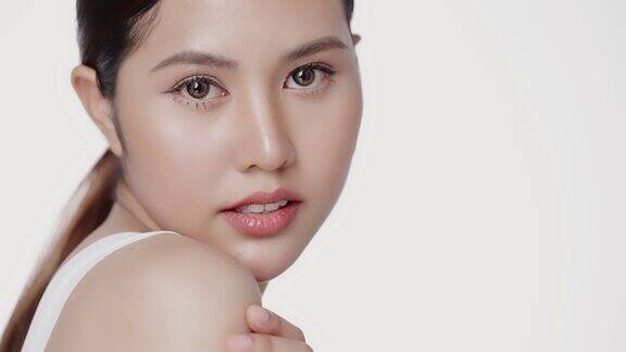 美丽年轻的亚洲女人的脸看着相机孤立在白色背景皮肤护理治疗或化妆品的广告概念