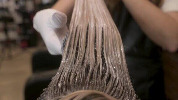 美容院的女发型师在顾客的头发上涂了发胶正在梳理