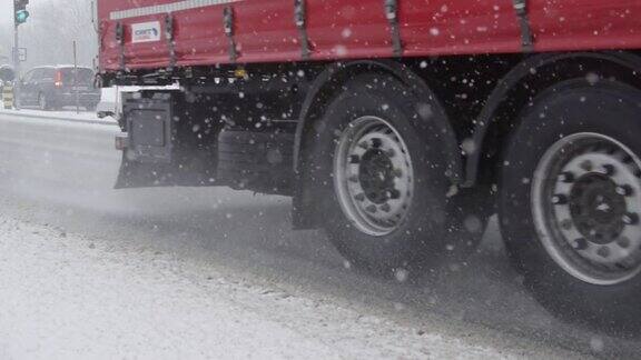 慢镜头:一辆载着货物的卡车在下雪天沿着光滑的道路行驶