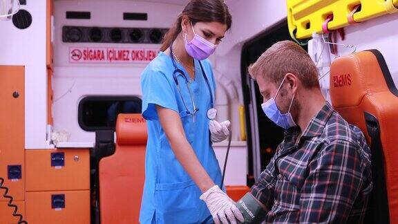 大流行期间戴着口罩的女护理人员在救护车上帮助病人并为病人测量血压