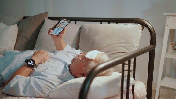 生病的老人与医生在线聊天在智能手机上进行视频咨询