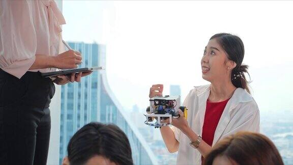 一位亚洲女高中生在课堂上与老师讲解并展示机器人项目