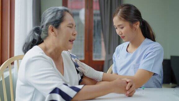 年长的亚洲妇女是在她的家中接受疫苗看护士用医疗注射器注射疫苗一位老人被隔离在家里公寓里