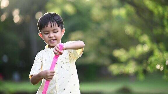 一个亚洲的中国小男孩在后院玩泡泡背光