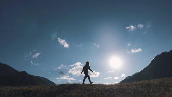 一个旅行者的剪影在山和天空的背景这个女游客正在山顶上散步