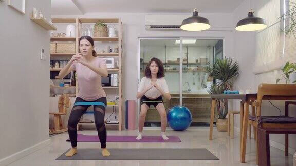 亚洲妇女和姐姐做深蹲与阻力带的重量训练