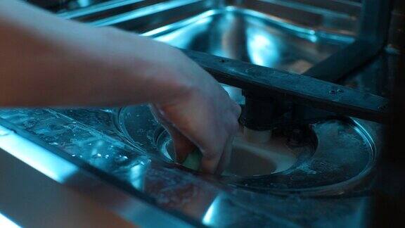 细节裁剪的镜头无法辨认的家庭主妇男性清洗擦拭洗碗机底部维修人员对家用设备进行维修的特写