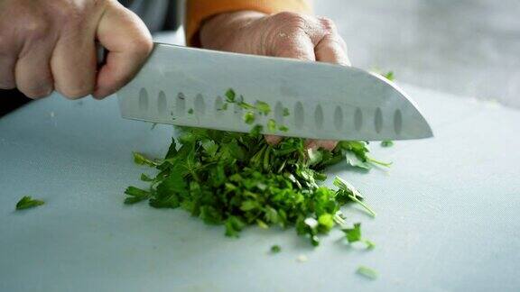 一位年长的白人妇女用菜刀在切菜板上切香菜