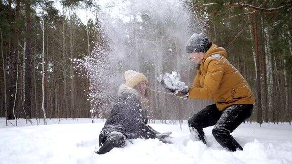 一对情侣女孩和男孩在冬天的森林里互相扔雪的慢镜头
