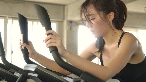 迷人的亚洲女人在健身车上做动感单车在健身房慢动作保健运动和运动