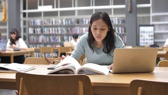 亚洲女学生在图书馆教育工作读书和做笔记