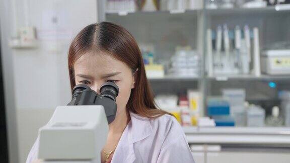 近景女生物学家在现代医学实验室显微镜下检查分析