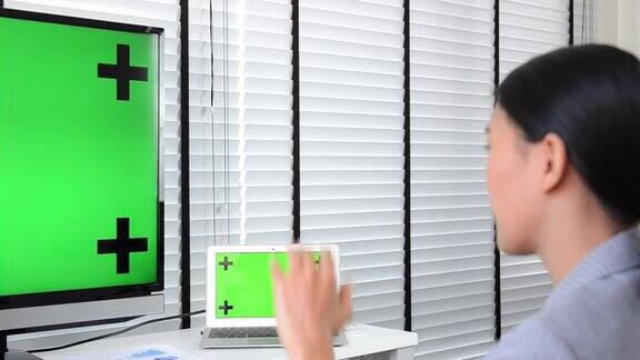 女商人在办公室用绿屏样机在电脑上工作绿屏键用于剪切