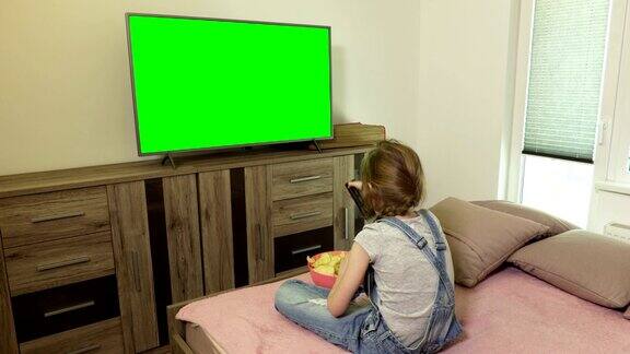 小女孩吃薯片看绿屏电视