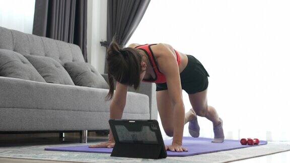 年轻的肌肉健身妇女做仰卧起坐锻炼在家里的客厅