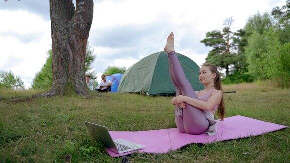 年轻女子在帐篷里观看在线视频练习普拉提