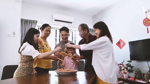 一个亚洲家庭在团圆饭期间用传统食物“生鱼”庆祝中国新年