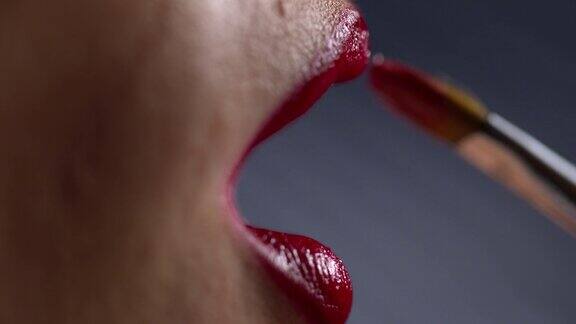 用化妆刷在女人的嘴唇上涂红色唇膏