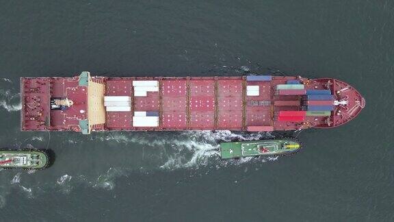 由拖船操纵装载货物集装箱的集装箱船的俯拍