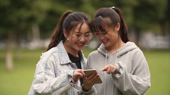 两个亚洲大学女孩在校园看手机