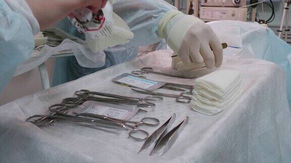 对宠物进行手术的开始外科医生从桌子上拿了一把手术刀助手打开无菌湿巾包把它们和器械一起放在桌子上