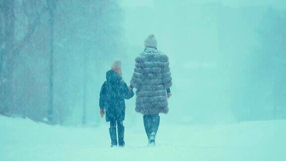 这位妇女带着孩子在冬天冒着大雪外出他们穿着毛皮大衣和靴子后视图