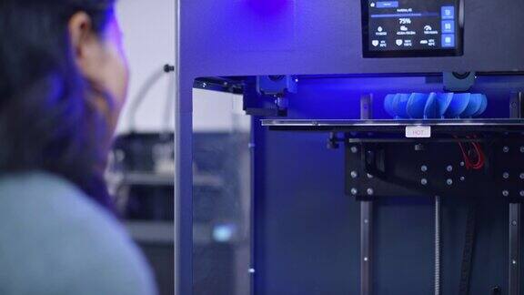 亚洲女工程师在3D打印机内监督模型的建造过程