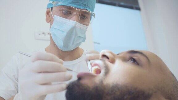 一名男性牙医使用口腔镜和牙齿探针