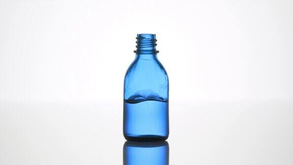 水滴落入蓝色医用瓶中液体溅起水花